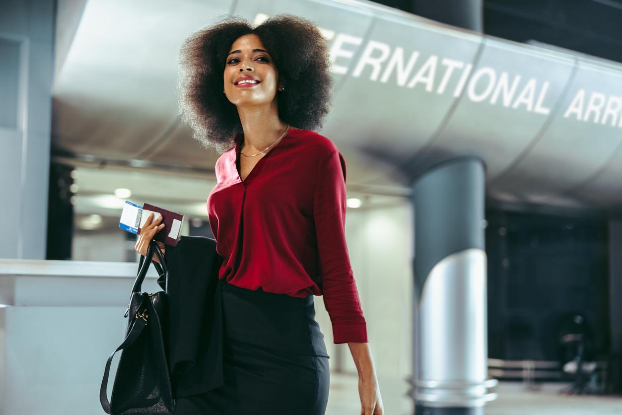 Kobieta podróżująca służbowo z kartą mile lotnicze w terminalu lotniska. Bizneswoman idąca korytarzem na międzynarodowym lotnisku.